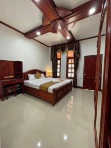 a bedroom with a large bed and a desk at PhaiLin Hotel in Luang Prabang