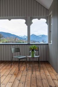 porche con 2 sillas, mesa y 2 ventanas en Chalet Vinzenz, Bildstein- mit privatem Ski- und Fahrradraum, en Bildstein