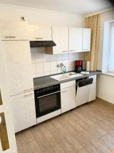 a kitchen with white cabinets and a sink and a stove at Ferienwohnungen Grimma 4 in Grimma