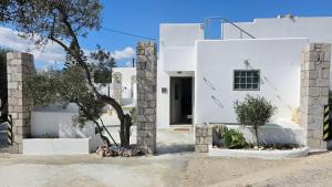 a white house with a tree in front of it at Olive In Blue in Adamas