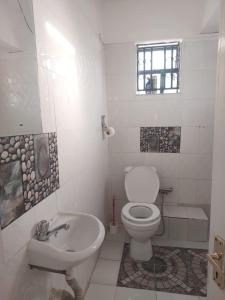 uma casa de banho branca com um WC e um lavatório em Skybeach apartment em Kisumu