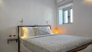 a bedroom with a bed with a window and two lamps at Olive In Blue in Adamas