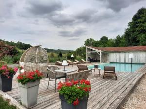 una terraza con piscina y una mesa con flores en CHARME AU FIL DE L'EAU, en Vendières