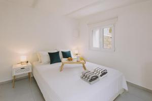 a white bedroom with a bed and a table at ARGi House in Maroulás