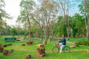 Comsaed River Kwai Resort SHA في مدينة كانشانابوري: رجل يركب دراجة في حديقة