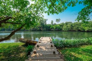 uma ponte de madeira sobre um rio com árvores em Comsaed River Kwai Resort SHA em Kanchanaburi