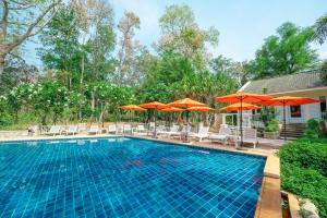 una piscina con sillas y sombrillas en Comsaed River Kwai Resort SHA, en Kanchanaburi