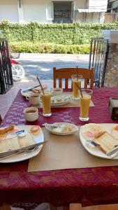 a table with plates of food and glasses of orange juice at PhaiLin Hotel in Luang Prabang