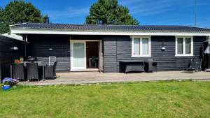 ein schwarzes Haus mit Stühlen und einem Tisch auf einer Terrasse in der Unterkunft Charming summer house close to the sea in Dronningmølle