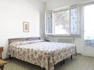 1 Schlafzimmer mit einem Bett mit Blumenbettdecke und einem Fenster in der Unterkunft Appartamento ALICE a Marina di Cecina in Marina di Cecina