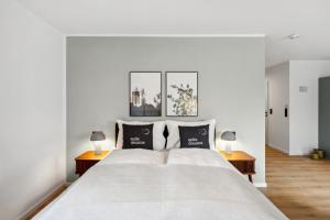 a white bedroom with a large white bed with two tables at limehome Salzburg Sterneckstr. in Salzburg