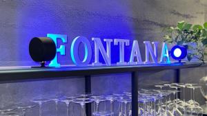 Un'insegna al neon che dice corona su uno scaffale con bicchieri da vino. di Hotel Fontana Verona a Verona