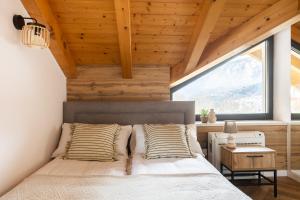 a bedroom with a bed and a large window at CASA IL TRAMONTO Val di Sole in Commezzadura