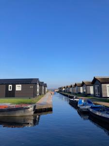 een rij huizen en boten in een kanaal bij Waterpark Giethoorn in Giethoorn
