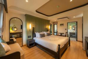 a bedroom with a large bed and a living room at Shamrock Chiangmai Hotel in Chiang Mai