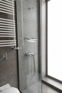 baño con ducha, aseo y puerta de cristal en Bright Loft With Terrance - Next to Metro Kerameikos en Atenas