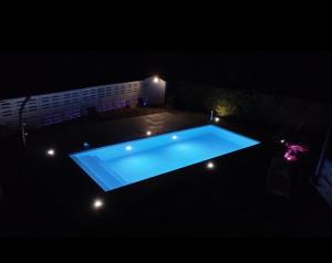 a swimming pool lit up at night with lights at B&B le palme mini appartamento mansardato in Bentivoglio