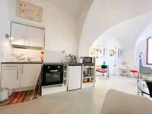 a kitchen with white cabinets and a living room at Le studio du Marquis in Marsanne