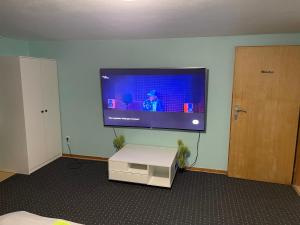 Habitación con TV de pantalla plana en la pared en Chambre avec 3 lits en Tréveris