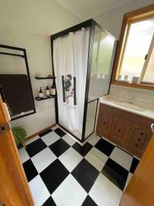 a bathroom with a shower and a black and white checkered floor at Cosy Guesthouse with River Views in Lenah Valley