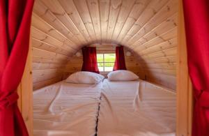 2 posti letto in una piccola camera con tende rosse di Recreatiepark Jachthaven De Veerstal Lathum - Luxe Chalet a Lathum