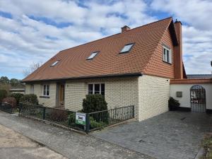 una casa con techo marrón y valla en gemütliche Ferienwohnung in Seenähe, en Neustrelitz