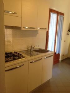 cocina blanca con fregadero y fogones en Appartamenti Rena Majore, en Aglientu