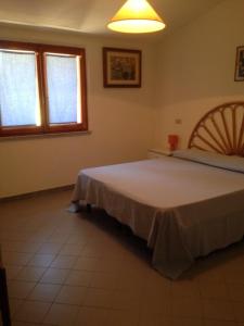 a bedroom with a large bed and two windows at Appartamenti Rena Majore in Aglientu
