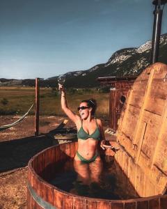 a woman in a bikini standing in a hot tub at Barrel Land Blidinje - Drvena bačva za spavanje in Posušje