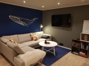a living room with a couch and a whale painting on the wall at Lofotlove Apartments - Modern and Comfy Apartments Close To Nature in Sørvågen