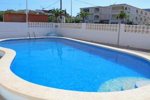 une grande piscine bleue à côté d'une clôture blanche dans l'établissement Apartamentos Bernat 3000, à Oropesa del Mar