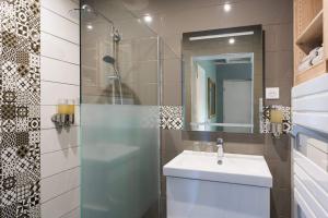 a bathroom with a sink and a shower with a mirror at Le Petit Rocher in Vienne