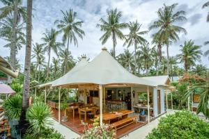 een paviljoen met een tafel en stoelen voor de palmbomen bij Gili Tenda in Gili Trawangan