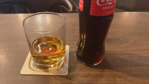 a glass of whiskey and a bottle on a table at Chambre avec 2 lits in Trier