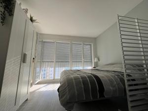 a bedroom with a bed and a large window at Logement entier : appartement proche de Paris ⸱ Chez Geoffrey in Châtillon