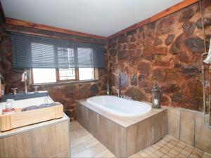 baño con bañera grande y pared de piedra. en Crooked Cottage, en Pelindaba 20 fotos más