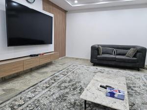 uma sala de estar com um sofá e uma televisão de ecrã plano em KAMS Clubhouse Lifecamp, 24 power em Abuja