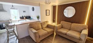 a living room with two chairs and a kitchen at Elmbank Garden Apartment in Oban
