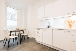 una cocina con armarios blancos y una mesa con sillas. en Schiller Apartment Neukölln, en Berlín