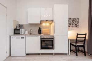 une cuisine avec des placards blancs et une table avec une chaise dans l'établissement Cosy Apartment nähe Potsdamer Platz, à Berlin