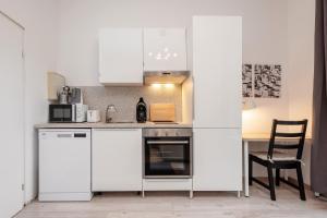 a kitchen with white cabinets and a table with a chair at Cosy Apartment nähe Potsdamer Platz in Berlin
