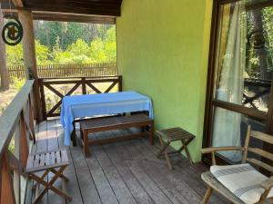 un porche con una mesa azul y bancos. en Zaciszny domek w sercu Puszczy Kampinoskiej, 