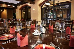 Royal Elephant Hotel & Conference Centre في سنتوريون: طاولة في مطعم به مناديل حمراء وكؤوس للنبيذ