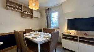 a dining room with a table with chairs and a television at Chez Nannou et Chris in Fort-Mahon-Plage