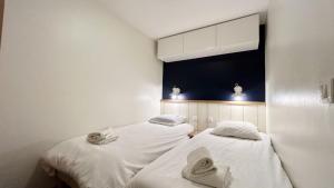 two beds in a room with white sheets and towels at Chez Nannou et Chris in Fort-Mahon-Plage