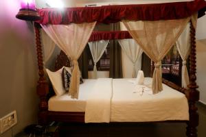 a bedroom with a canopy bed with curtains at Falcon Resorts by Dia Hotels in Calangute