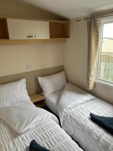 2 Betten in einem kleinen Zimmer mit Fenster in der Unterkunft Harries Lodge 2 Aberaeron in Aberaeron