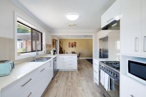 a kitchen with white cabinets and a large window at Spacious House with Pool - 5 min walk to Lake in Wyong