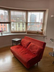 a red couch in a living room with windows at The Cherry Blossom in Bristol