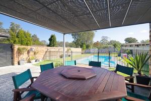 a patio with a wooden table and chairs and a pool at Spacious House with Pool - 5 min walk to Lake in Wyong